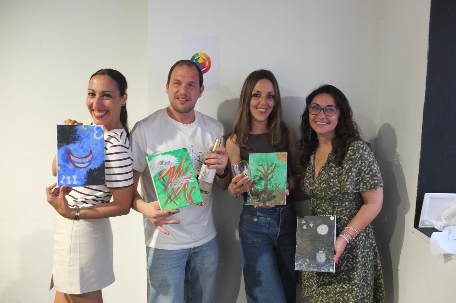 Participantes con sus obras finales y una botella de vino