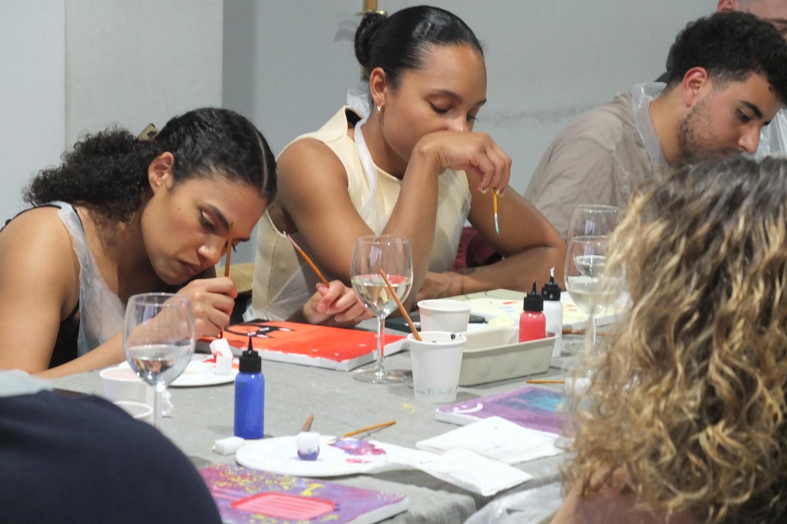 Personas concentradas pintando con una copa de vino
